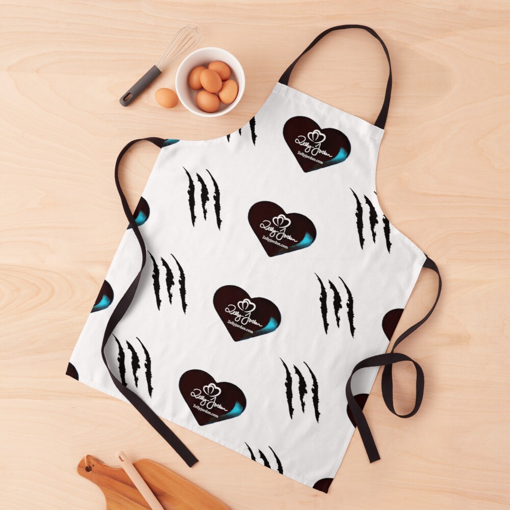 A white apron featuring a pattern of black claw marks and a heart logo with blue accents, placed on a wooden surface with a bowl of eggs and a whisk.