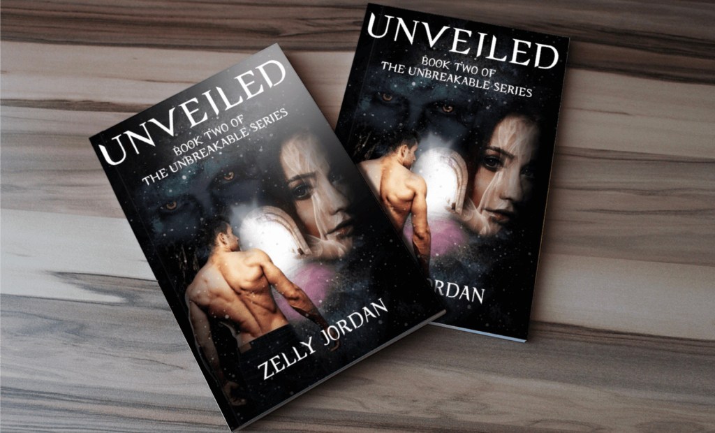 Two copies of the book 'Unveiled' by Zelly Jordan, featuring artistic covers with themes of fantasy and romance, displayed on a wooden surface.